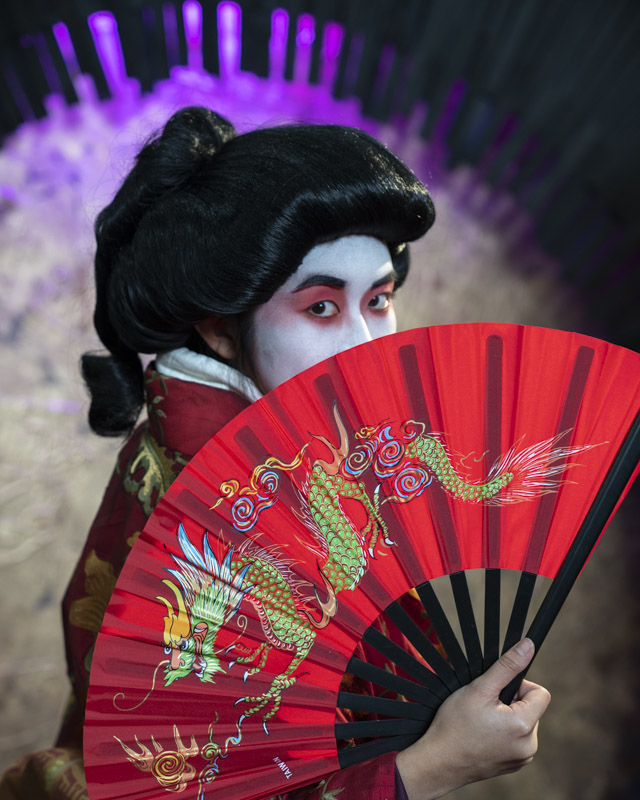 A striking portrait of tradition and artistry, where bold color, intricate detail, and a piercing gaze come together in a moment of timeless cultural expression.